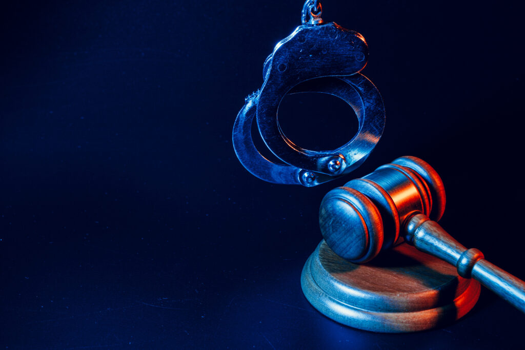 Judge gavel and handcuffs on dark black background